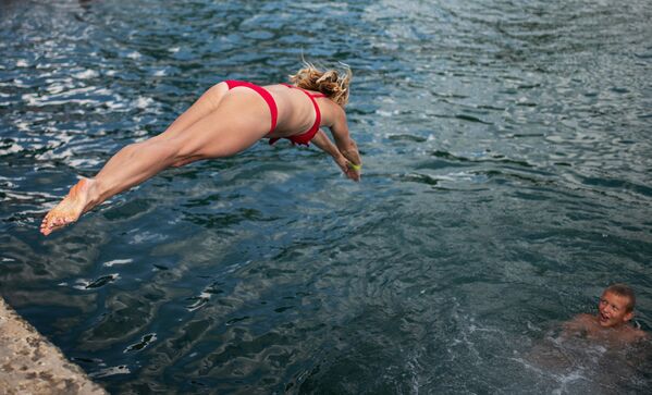 Девушка прыгает с пирса на пляже в Ялте