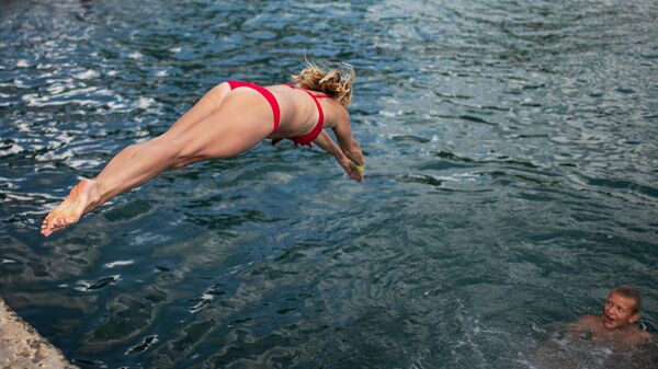Девушка прыгает с пирса на пляже в Ялте