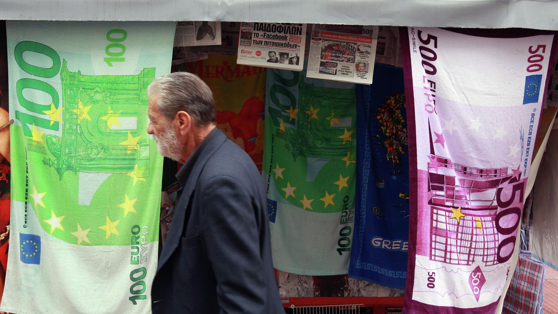 Мужчина проходит мимо киоска, торгующего полотенцами в виде банкнот евро в Афинах - РИА Новости, 1920, 20.03.2022