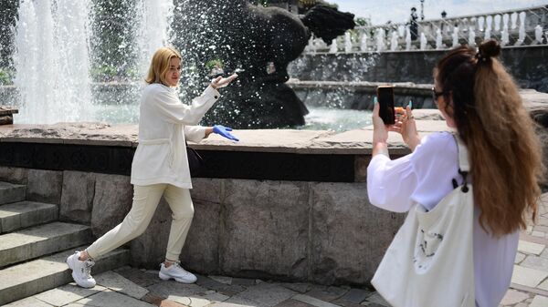 Девушки фотографируются  у фонтана в Александровском саду в Москве
