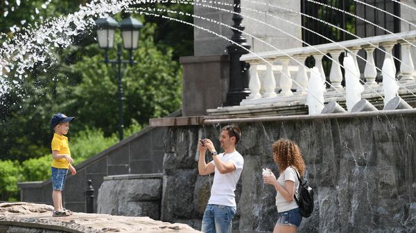 Отдыхающие фотографируются у фонтана в Александровском саду в Москве