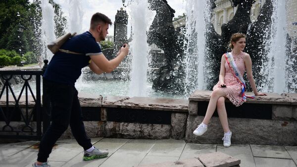 Молодые люди фотографируются у фонтана в Александровском саду в Москве