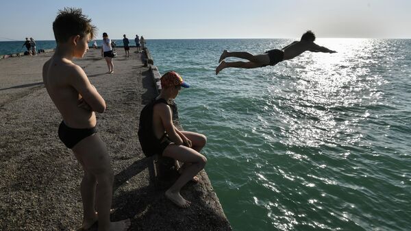 Юноша прыгает с пирса в море на набережной в поселке Новофедоровка Сакского района