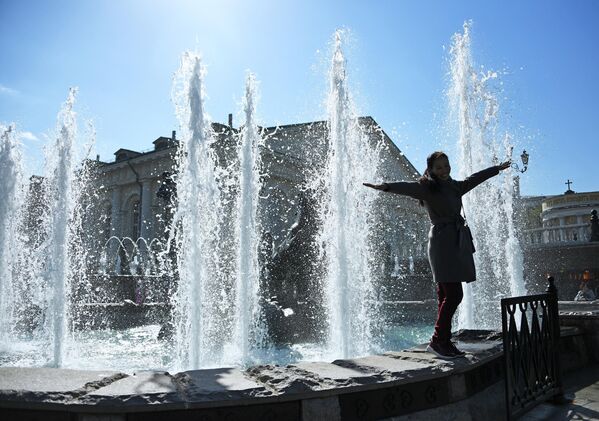 Девушка фотографируется у фонтана Времена года на Манежной площади в Москве