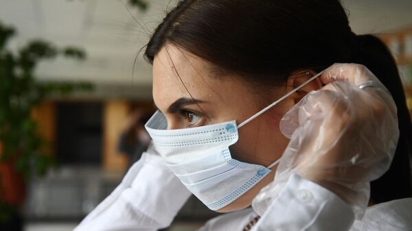Девушка надевает маску во время демонстрации работы модельного участка для общероссийского голосования по поправкам в Конституцию РФ