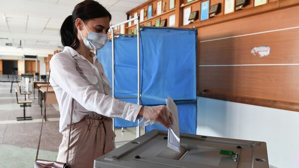 Девушка опускает бюллетень в урну во время демонстрации работы модельного участка для общероссийского голосования по поправкам в Конституцию РФ