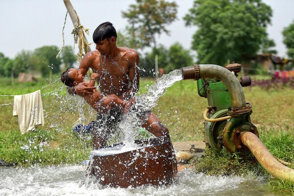 Мужчина обливает сына водой во время жары в Нью-Дели