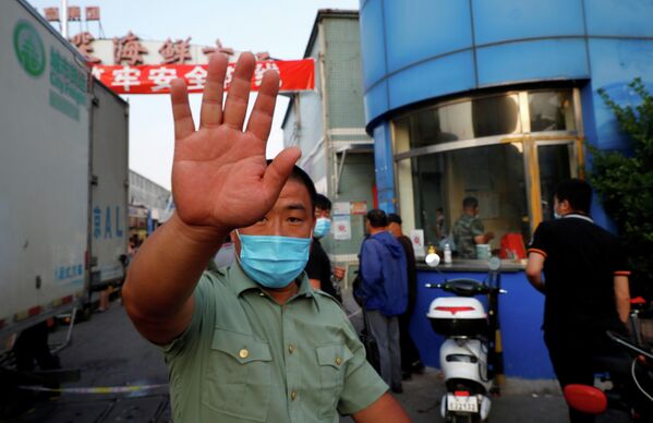 Охранник в маске возле рынка морепродуктов Jingshen в Пекине, Китай
