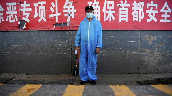 Охранник в защитной костюме на контрольно-пропускном пункте на рынке Синьфади в Пекине, Китай