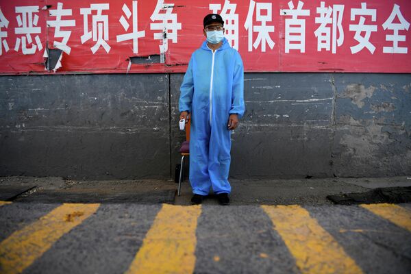 Охранник в защитной костюме на контрольно-пропускном пункте на рынке Синьфади в Пекине, Китай