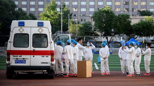 Медицинские работники в спортивном центре Guang'an, где проходит тестирование людей на коронавирус, живущих рядом или посещающих рынок Синьфади