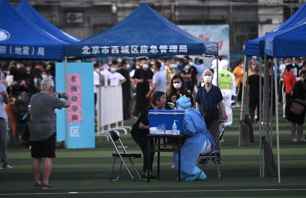 Тестирование людей на коронавирус, живущих рядом или посещающих рынок Синьфади в спортивном центре Guang'an в Пекине, Китай