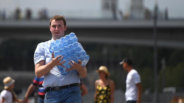 Прохожий с упаковкой питьевой воды в окрестностях парка Зарядье в Москве