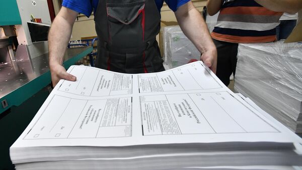 Сотрудник типографии берет пачку напечатанных бюллетеней для голосования по внесению поправок в Конституцию РФ