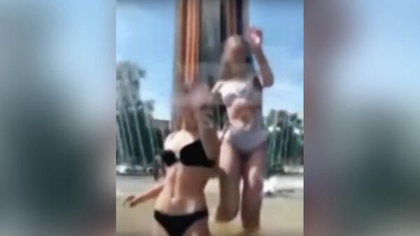 Кадр видео, на котором две девушки в купальниках танцуют в фонтане у мемориала Победы в Калуге