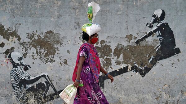 Женщина в защитной маске проходит мимо граффити после ослабления карантинных мер в Мумбаи