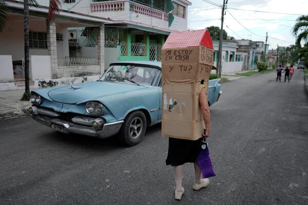 Пенсионерка и бывшая медсестра Феридия Рохас идет по улице Гаваны во время пандемии коронавируса, надев картонную коробку с надписью Я дома. А ты?