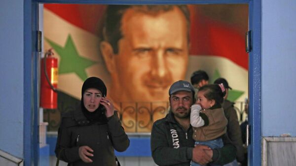 Люди проходят мимо портрета Башара Асада в Дамаске 