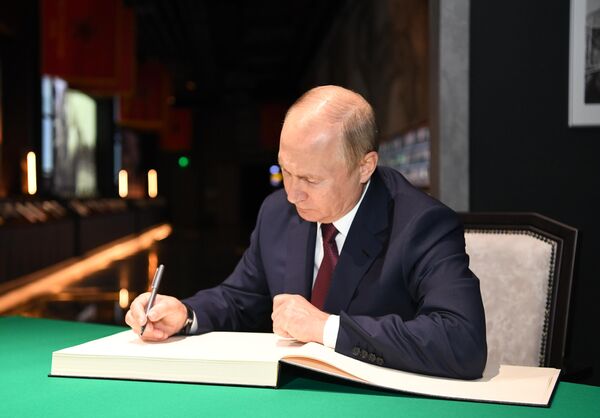 Президент РФ Владимир Путин оставляет запись в книге почетных посетителей во время посещения главного храма Вооружённых Сил