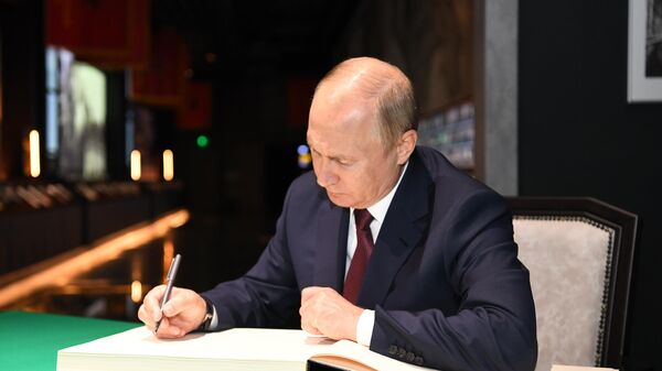 Президент РФ Владимир Путин оставляет запись в книге почетных посетителей во время посещения главного храма Вооружённых Сил
