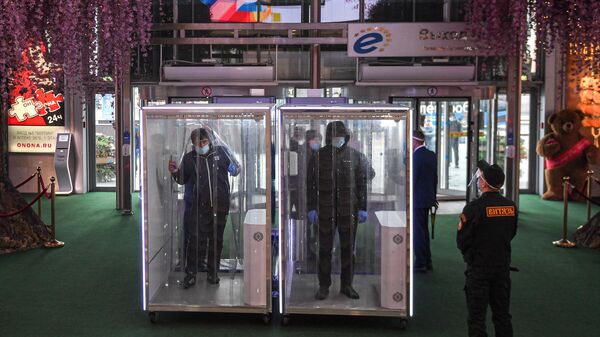 Посетители проходят через кабины дезинфекции при входе в торговый центр Европейский