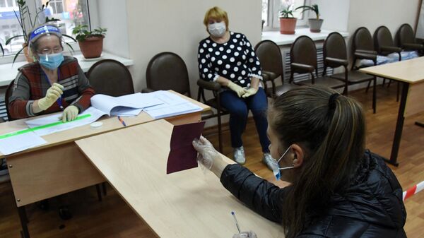 Член избирательной комиссии регистрирует участницу голосования по внесению поправок в Конституцию РФ на избирательном участке №727 во Владивостоке