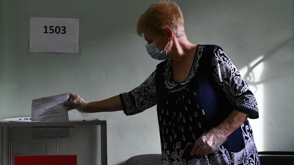 Женщина принимает участие в голосовании по внесению поправок в Конституцию РФ на избирательном участке