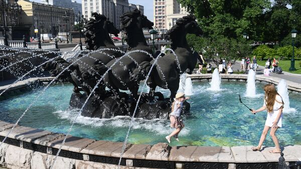 Дети играют возле фонтана в жаркий день на Манежной площади в Москве