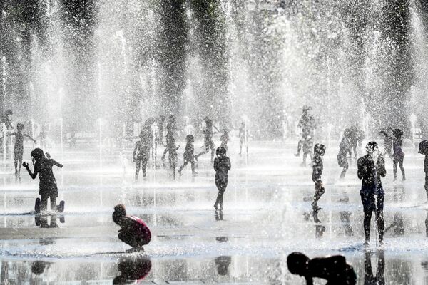 Дети купаются в фонтане во время жары в Ницце 