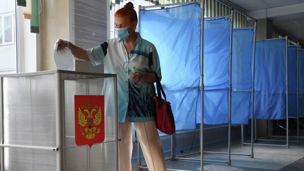 Женщина принимает участие в голосовании по внесению поправок в Конституцию РФ на избирательном участке 