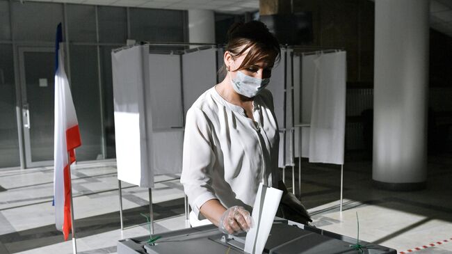 Женщина голосует по одобрению внесения поправок в Конституцию РФ на избирательном участке в Симферополе