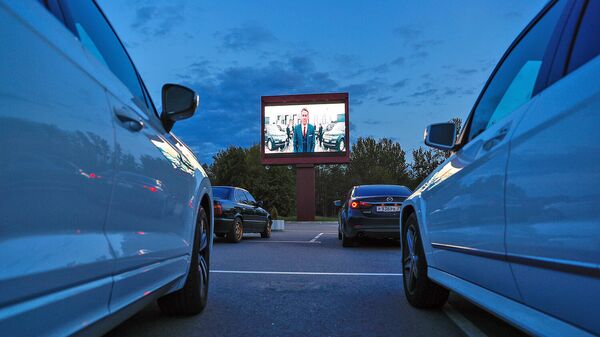 Легковые автомобили со зрителями во время киносеанса в автокинотеатре