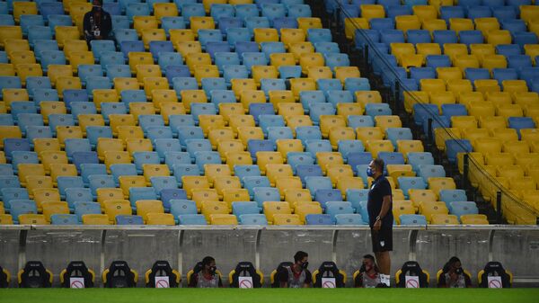 Flamengo team players remain sitting on the bench respecting security distances during a Carioca Championship 2020 football match against Bangu at the Maracana stadium, in Rio de Janeiro, Brazil, on June 18, 2020, which is played behind closed doors as the city gradually eases its social distancing measures aimed at curbing the spread of the COVID-19 coronavirus. (Photo by MAURO PIMENTEL / AFP)