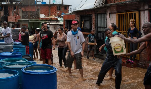 Люди набирают питьевую воду в различные емкости. В связи с трудностями в водоснабжении, жители некоторых районов Каракаса вынуждены ждать дождя, чтобы иметь возможность получить воду