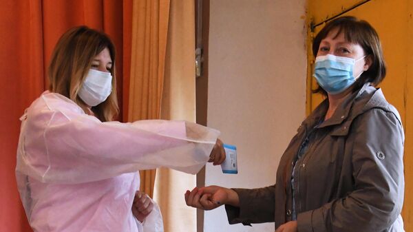 Женщине измеряют температуру при входе на избирательный участок во Владивостоке, где проходит голосование по вопросу внесения поправок в Конституцию РФ