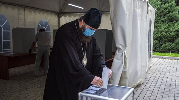 Священнослужитель принимает участие в голосовании по внесению поправок в Конституцию РФ на избирательном участке в Бишкеке