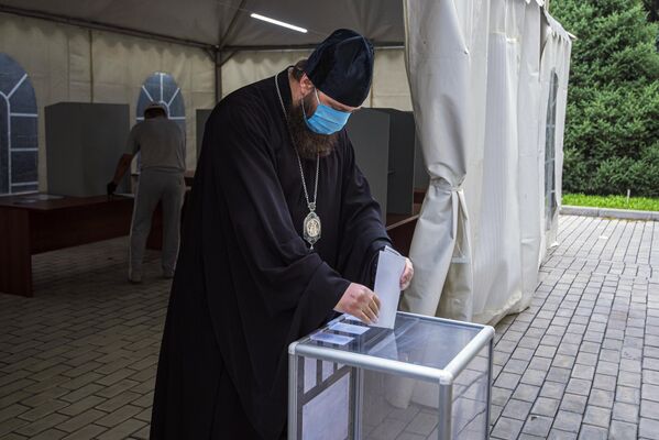 Священнослужитель принимает участие в голосовании по внесению поправок в Конституцию РФ на избирательном участке в Бишкеке