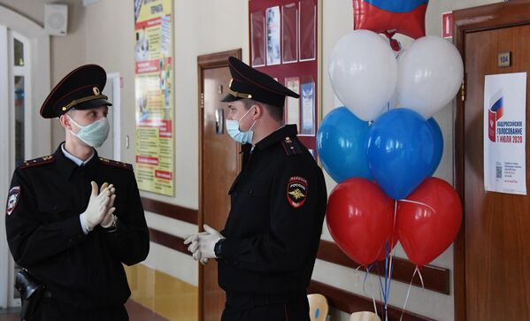 Сотрудники полиции дежурят во время голосования по вопросу одобрения изменений в Конституцию России на избирательном участке в средней школе №6 во Владивостоке