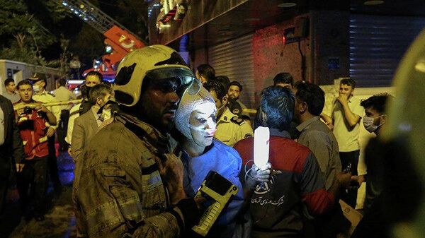 Пожарный помогает пострадавшей женщине на месте взрыва в медицинской клинике в Тегеране
