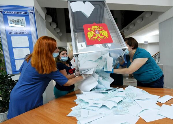 Члены избирательной комиссии вынимают бюллетени из урн на избирательном участке №101 во время подсчета голосов по итогам голосования по поправкам в Конституцию РФ в Саяногорске