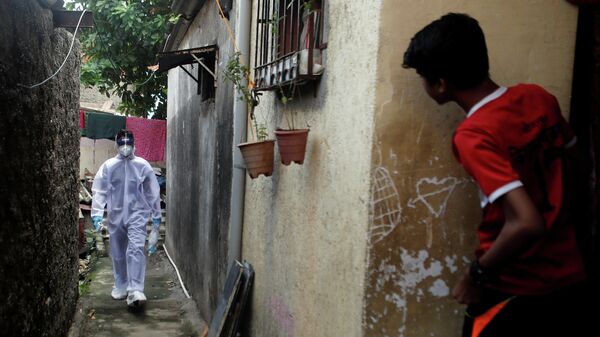Медицинский работник в защитном костюме идет по улице в Мумбаи, Индия 