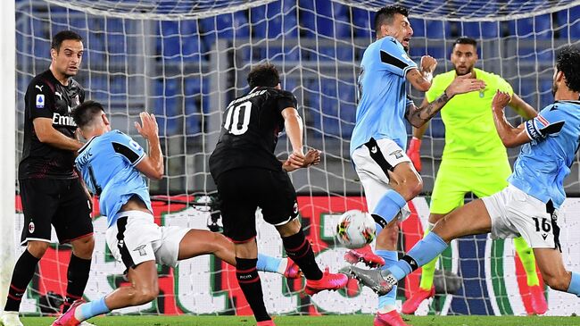 AC Milan's Turkish forward Hakan Calhanoglu (C) shoots to open the scoring during the Italian Serie A football match Lazio vs AC Milan played behind closed doors on July 4, 2020 at the Olympic stadium in Rome, as the country eases its lockdown aimed at curbing the spread of the COVID-19 infection, caused by the novel coronavirus. (Photo by Tiziana FABI / AFP)