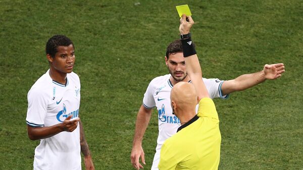 Сергей Карасев показывает желтую карточку игроку Зенита Вильмару Барриосу (слева)