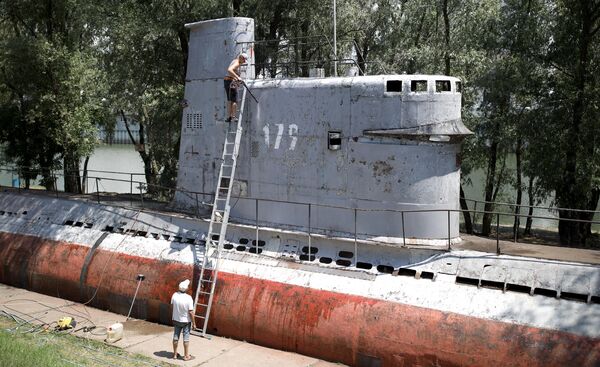 Местные жители чистят корпус малой многоцелевой дизельной подводной лодки М-261, установленной в парке 30-летия Победы в Краснодаре