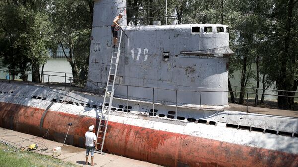 Местные жители чистят корпус малой многоцелевой дизельной подводной лодки М-261, установленной в парке 30-летия Победы в Краснодаре