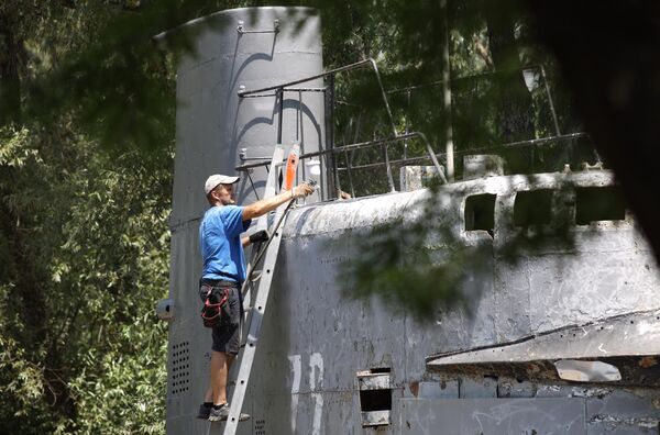 Мужчина красит корпус малой многоцелевой дизельной подводной лодки М-261, установленной в парке 30-летия Победы в Краснодаре
