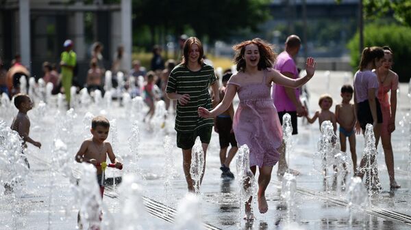 Люди отдыхают у фонтана в жаркий день в парке искусств Музеон
