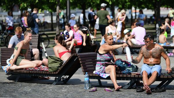 Люди отдыхают у фонтана в жаркий день в парке искусств Музеон