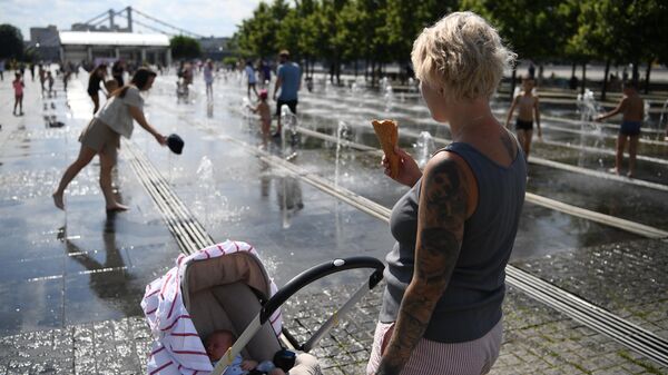 Женщина с ребенком у фонтана в жаркий день в парке искусств Музеон