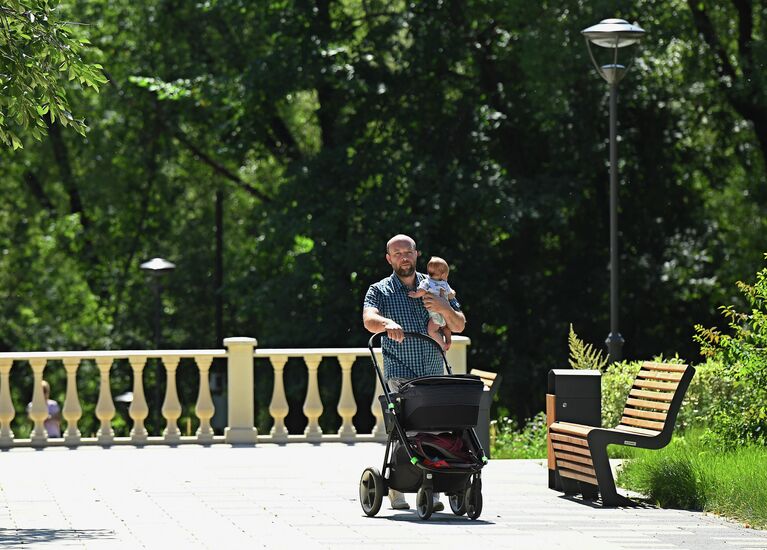 Мужчина гуляет с ребенком в парке Сад будущего в Москве